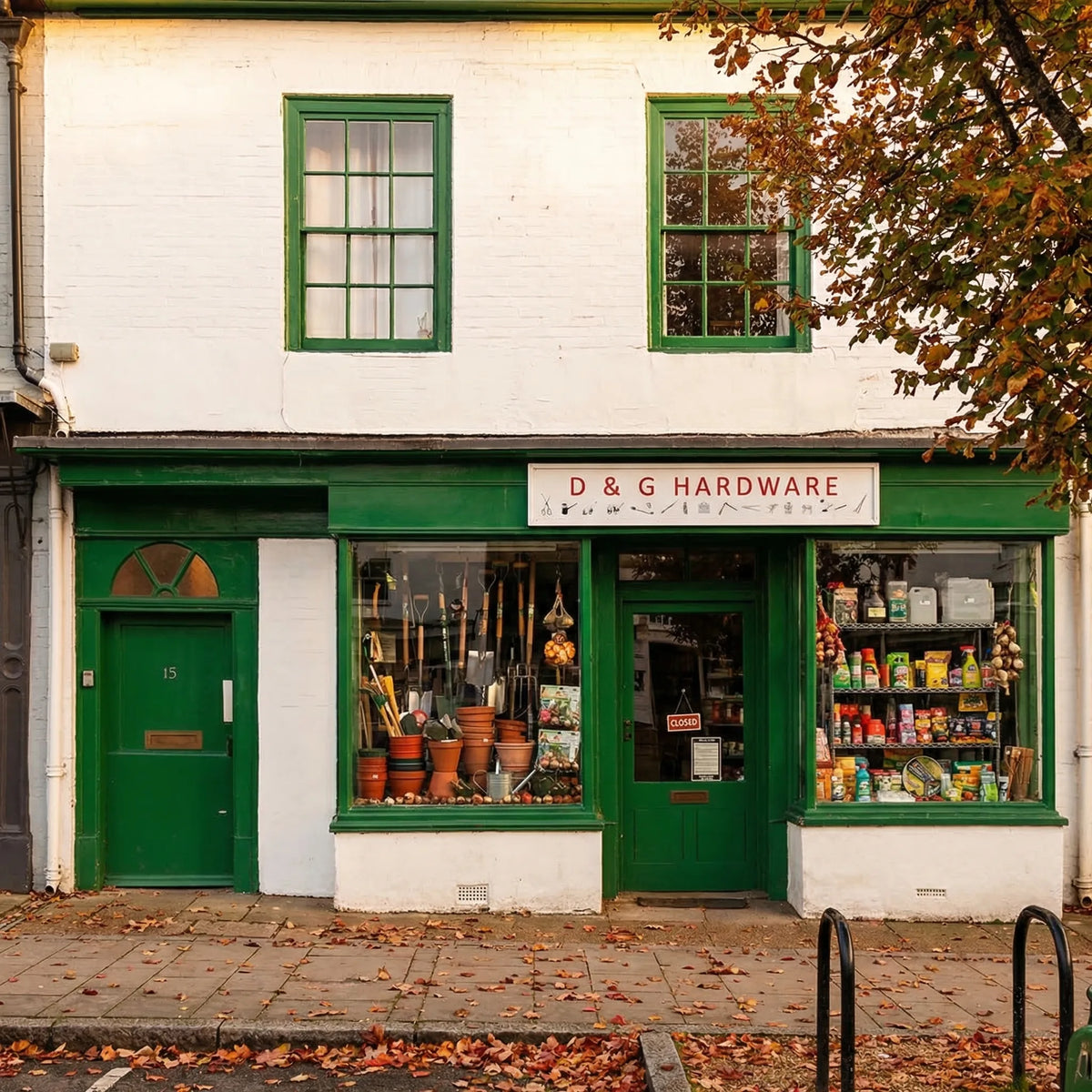 Green and white building with 'D & G Hardware' sign, surrounded by autumn leaves.